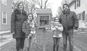  ??  ?? Rhiannon and Jose Adams pose for a photo with their children, Ana, left, and Emma, next to the Little Blue Pantry they installed outside their home in Waukesha. Ten-year-old Ana came up with the idea for helping those in need throughout her community.