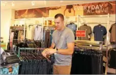  ?? MICHILEA PATTERSON — DIGITAL FIRST MEDIA ?? Justin Meade, manager of the local active wear RBX retail store, hangs clothes. The store was recently opened inside the Philadelph­ia Premium Outlets in Limerick.