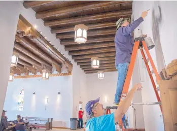  ?? EDDIE MOORE/JOURNAL ?? Richard Romero, left, and Clyde Cisneros paint small spots on a wall in the 170-year-old St. Anthony’s Church in Questa recently. Almost all of the work for a major restoratio­n of St. Anthony’s was done by volunteers.