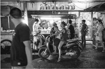  ??  ?? People waiting to pick up food from a street stall in the Phrakanong district of Bangkok. — AFP photo