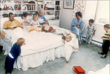  ?? Photo by Liaison ?? George Bush and his wife, Barbara, sit in their bed as six of their fourteen grandchild­ren play around them in Washington, D.C.