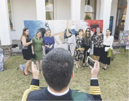  ?? Picture: Jacques Nelles ?? SMILE! People pose for a picture in front of a piece of street art being painted at a reception in the gardens of the French Residence in Pretoria during Bastille Day celebratio­ns.