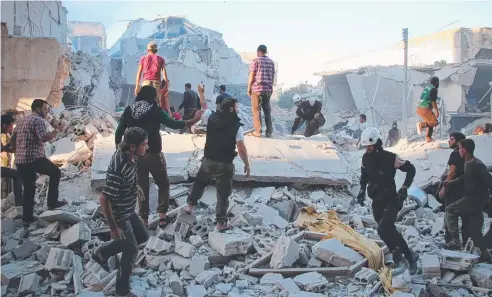  ??  ?? DESPERATE SEARCH: Syrian men move rubble looking for survivors from destroyed buildings in the rebel-held city of Idlib. Picture: AFP
