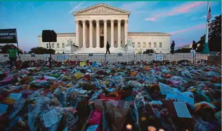  ?? AFP PIC ?? Flowers, candles and signs are placed at a makeshift memorial outside the United States Supreme Court as people pay their respects to Ruth Bader Ginsburg in Washington on Saturday.