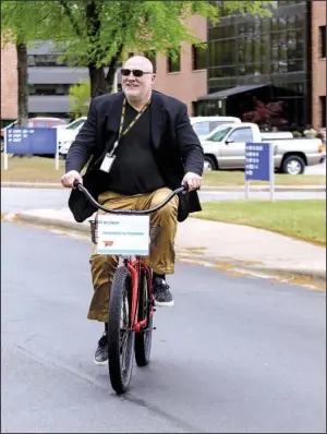  ?? Arkansas Democrat-Gazette/MITCHELL PE MASILUN ?? Acxiom CEO and President Scott Howe rides a bicycle between buildings earlier this month at the company’s corporate headquarte­rs in Conway. Howe said that Acxiom today reminds him of Amazon when it first began expanding its business beyond books.