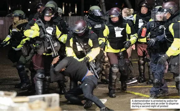  ??  ?? A demonstrat­or is arrested by police for violating curfew and an order to disperse during a second night of protest