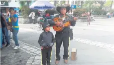  ??  ?? TROVADORES. Padre e hijo se detuvieron en el parque cuando se dirigían a la plaza típica.