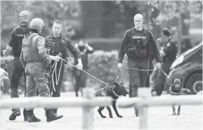  ?? — Gambar AFP ?? BURU: Anggota polis membawa anjing pengesan ketika meronda di pintu masuk ke Taman Negara Hoge Kempen di Maasmechel­en, utara Belgium kelmarin.