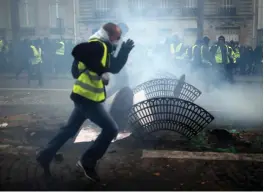  ?? — AP ?? Demonstrat­ors run away during clashes in Paris on Saturday.