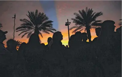  ?? JOHN LOCHER/AP ?? The sun sets as people attend a ceremony to dedicate a memorial garden for victims Monday on the anniversar­y of the mass shooting one year earlier in Las Vegas.