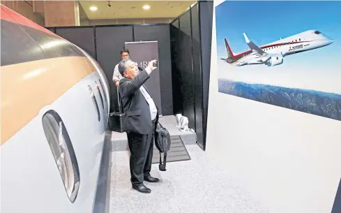  ?? REUTERS ?? A visitor takes a picture of a poster of Mitsubishi Regional Jet (MRJ) during Japan Aerospace 2016 air show in Tokyo.
