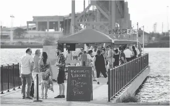  ?? NICK BRANCACCIO ?? Guests arrive for the WindsorEat­s’ Dinner on a Pier event at Ambassador Park. Foodies in attendance dined on an eclectic array of Spanish dishes with their tables pushed together for a communal ambience.