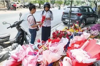  ?? — AFP photos ?? A student (right) buys flowers on Valentine’s Day in Phnom Penh.