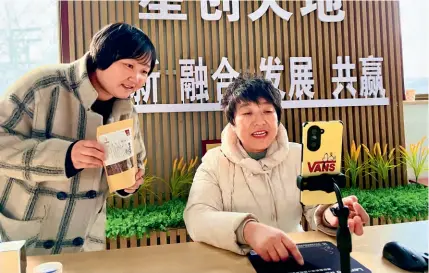  ?? ?? Wang Shiling (right) teaches a farmer how to sell nuts with a smartphone