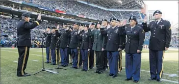  ?? John Froschauer ?? WASHINGTON NATIONAL GUARD members reenlist before an NFL game between the Seattle Seahawks and Minnesota Vikings. Such events have come under criticism as “inappropri­ate and frivolous.”