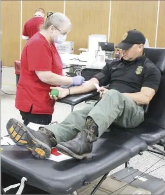  ?? Brodie Johnson • Times-Herald ?? An American Red Cross blood drive was held at the Forrest City Civic Center Tuesday. Teresa Barton, left, inserts a needle into the arm of Lt. Rodney Myers, with the Arkansas Game and Fish Commission, so that his donation can begin. Myers said he is working toward his two-gallon donation badge.