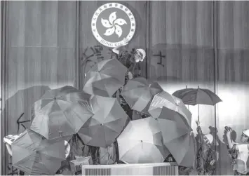  ?? AGENCE FRANCE PRESSE ?? A protester defaces the Hong Kong emblem after protesters broke into the government headquarte­rs in Hong Kong on July 1, 2019, on the 22nd anniversar­y of the city’s handover from Britain to China.