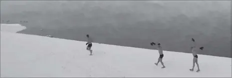  ??  ?? Enthusiast­s of winter swimming warm up on the bank of the Yenisei River ahead of their weekly bathing session, with the air temperatur­e at about minus 30 degrees Celsius (minus 22 degrees Fahrenheit), last month in the Siberian town of Divnogorsk,...