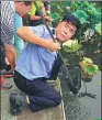  ?? PROVIDED TO CHINA DAILY ?? Hangzhou police officer Zhou Xiangjun helps a visitor in August to retrieve an item that had fallen into West Lake.