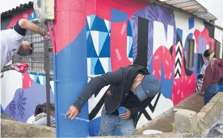  ?? Picture: AFP ?? Victims of Colombia’s armed conflict paint graffiti, using the term unity, on the facade of the pastoral house in an impoverish­ed neighbourh­ood in Soacha, south of Bogota. According to official figures, 10% of the 530 000 residents are victims of...