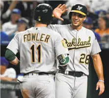  ?? Ed Zurga / Getty Images ?? Matt Olson congratula­tes Dustin Fowler after his three-run homer in the ninth. The pair combined for nine RBIs.