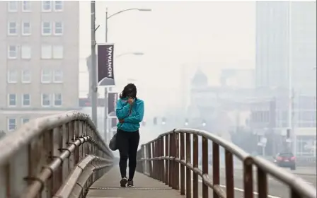  ?? — AP ?? Hazardous atmosphere: A woman walking to work in Missoula, Montana, as smoke from the nearby Lolo Peak fire fills the air.