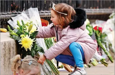  ??  ?? CAREFUL: A young girl places a small bouquet at Buckingham Palace