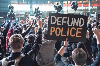  ?? JOHN MINCHILL/ AP ?? A protester holds a sign that reads "Defund Police" during a rally for the late George Floyd outside Barclays Center in New York last year.