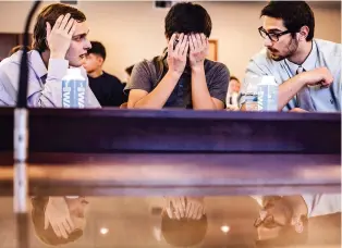  ?? PHOTOS BY GABRIELA CAMPOS/THE NEW MEXICAN ?? From left, Scott Manning, Skye Stone and Hemza Assed, from Albuquerqu­e Academy, deliberate over the answer to a question during the final rounds of the Academic World Quest event Thursday at Santa Fe Community College.