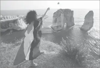  ?? Hussein Malla / aP ?? A Lebanese activist wearing a Palestinia­n flag throws a flower into the sea near Pigeons’ Rock in Beirut on Tuesday during a protest against the war in Gaza.