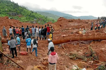  ?? PHOTO: REUTERS ?? Residents watch as rescue workers search for survivors after a mudslide in the mountain town of Regent, Sierra Leone.