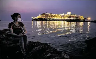  ?? Paula Bronstein / Getty Images ?? A Chinese woman looks at the Westerdam cruise ship docked nearby in Sihanoukvi­lle, Cambodia, on Monday. There are still 255 passengers and 747 crew members on board waiting.