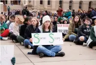  ?? The Flint Journal via AP ?? ■ Protesters hold signs to protest gun violence Wednesday at a student sit-in at the Michigan Capitol building following a mass shooting at Michigan State University earlier in the week in Lansing, Mich.