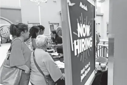  ?? LYNNE SLADKY/AP ?? People inquire about job openings during a job fair in Miami. The proportion of Americans who either have a job or are looking for one declined to just under 60%, according to the Labor Department’s latest jobs report.