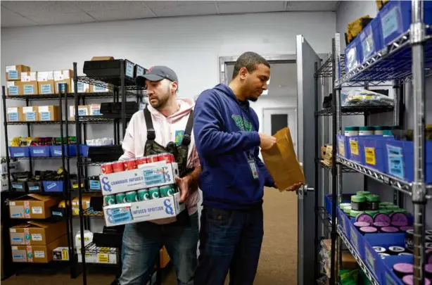 ?? PHOTOS BY DANIELLE PARHIZKARA­N/GLOBE STAFF ?? Bryce Hall (left) carried cannabis-infused seltzers as Devin Alexander filled a delivery order at Rolling Releaf, a dispensary in Newton.