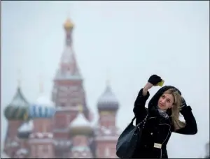  ?? AP/PAVEL GOLOVKIN ?? A woman takes a selfie in the snow Wednesday in Moscow’s Red Square. The Russian economy, which relies on its oil and gas industry, is slowing because of a drop in global energy prices.