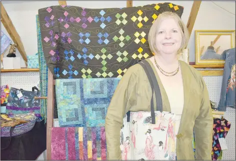  ?? (NWA Democrat-Gazette/Rachel Dickerson) ?? Lenora Babb carries a Japanese-inspired bag that she made. Behind her are a few quilts that she sewed. Her work is on display at the Wishing Spring Gallery on McNelly Road.