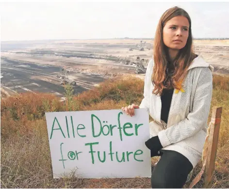  ?? FOTO: DAVID YOUNG/DPA ?? Luisa Neubauer im August 2020 mit einem Protestpla­kat am Rande des Tagebaus Garzweiler bei Jüchen.