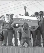  ?? LUIS ROBAYO/ AFP-GETTY IMAGES ?? Protesters stand atop a container used as a roadblock in Venezuela.