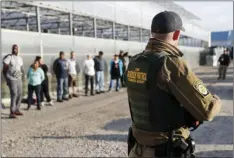  ??  ?? Government agents stand guard alongside suspects taken into custody during an immigratio­n sting at Corso’s Flower and Garden Center on Tuesday in Castalia, Ohio. The operation is one of the largest against employers in recent years on allegation­s of...