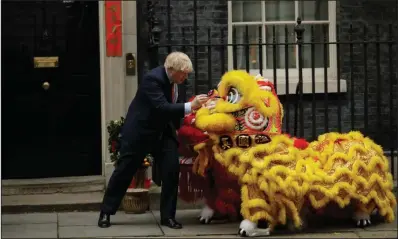  ??  ?? British Prime Minister Boris Johnson dots the eyes with paint Friday on a lion costume worn by performers as he welcomes members of the British Chinese community for Lunar New Year celebratio­ns outside his residence at No. 10 Downing St. in London. Also Friday, Johnson put his signature on an exit agreement with the European Union, but with no news photograph­ers present. (AP/Matt Dunham)