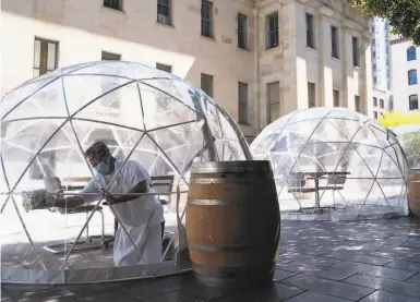  ?? Photos by Sarahbeth Maney / The Chronicle ?? Toku Mekaru of S.F. disinfects one of Hashiri’s dining domes Aug. 6, on Mint Plaza off Fifth Street.