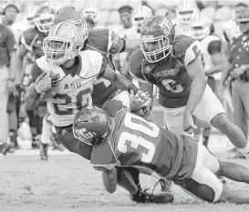  ?? Tim Warner ?? Texas Southern’s Archie Rice, bottom, and Sean Jones, right, combine to bring down Alabama State running back Ezra Gray on this second-quarter run.