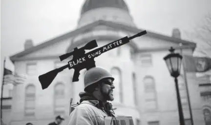  ?? Robert F. Bukaty, The Associated Press ?? Joe Dobbins of Hartford, Maine, wears a cutout of a tactical rifle on his helmet at a gun rights rally Saturday at the state Capitol in Augusta.