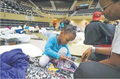  ?? Rick Hickman, American Press ?? Keturah Sadler and her daughter Aniyah color together in the Lake Charles Civic Center in Louisiana on Wednesday. They were rescued from rising water inside their home Tuesday night.