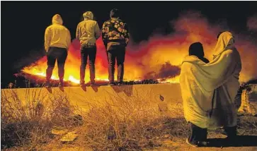  ?? Robert Gauthier Los Angeles Times ?? OXNARD RESIDENTS watch the flames from a cul-de-sac near the 126 Freeway on Thursday night. About 8,000 residents of the area have been evacuated, and thousands of structures are threatened.