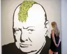  ?? — AFP ?? A gallery assistant poses with ‘ Turf War’ 2003 artwork ( above) and ‘ Kissing Coppers’ 2006 artwork ( left) by Banksy at Lazinc Gallery in London on Wednesday. The British street artist has made his name with clandestin­e street murals and a treasure...