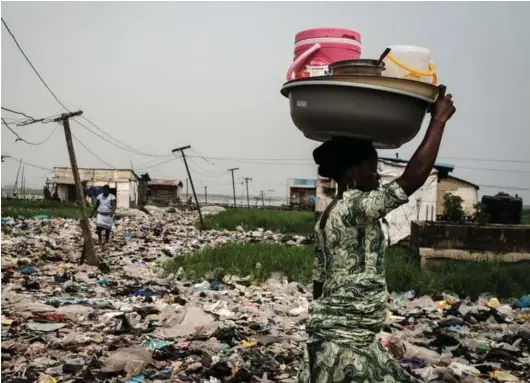  ?? ?? ► Una mujer camina sobre desechos plásticos, utilizados para recuperar un pantano y poder construir casas, en Lagos, Nigeria.