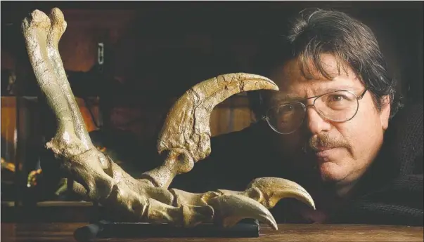  ??  ?? Kirkland looks at a reconstruc­ted foot of a Utahraptor dating back 125 million years at the Utah Division of Natural Resources office.