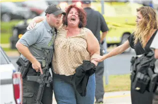  ?? Steve Apps / Associated Press ?? A woman is escorted from a software company in Middleton, Wis., where four people were shot and wounded on Wednesday. Middleton is a suburb of Madison, the state capital.